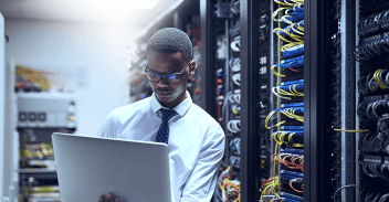 Worker running compliance checks on laptop in data centre 